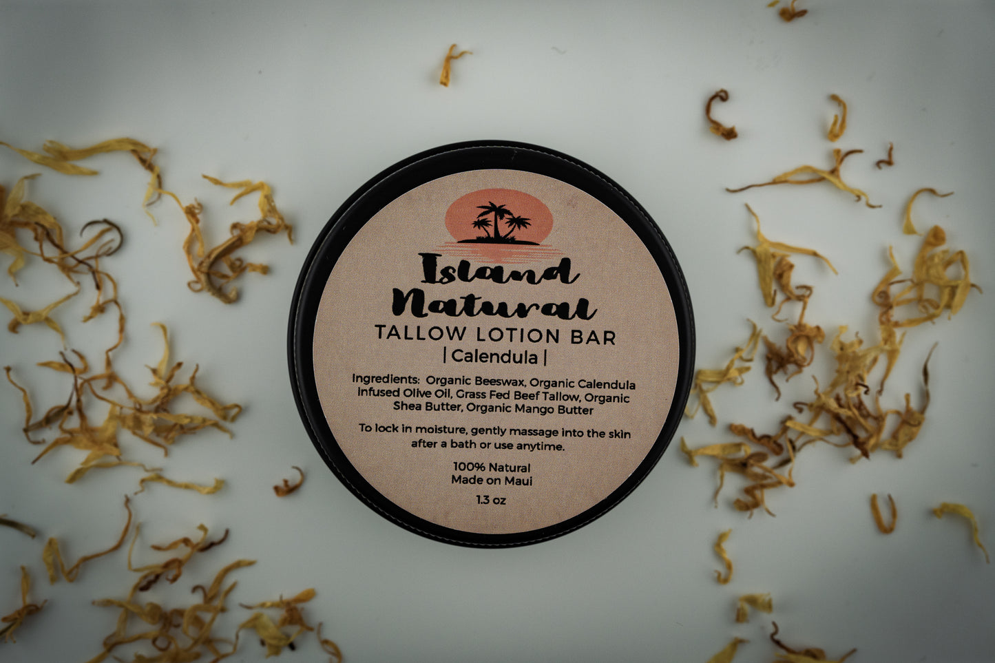 Island Natural Skincare Tallow Lotion Bar on a white background with dried herbs