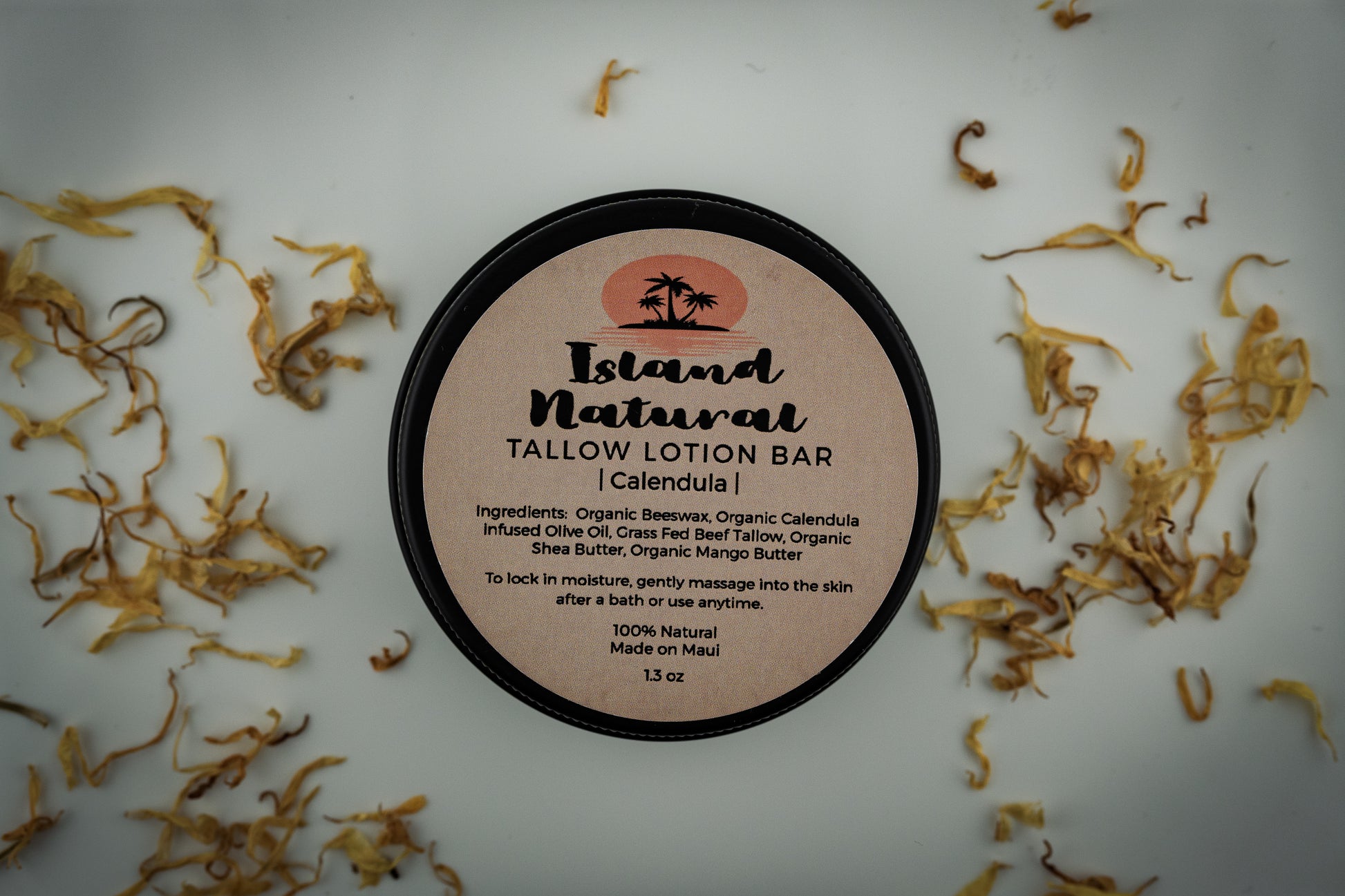 Island Natural Skincare Tallow Lotion Bar on a white background with dried herbs