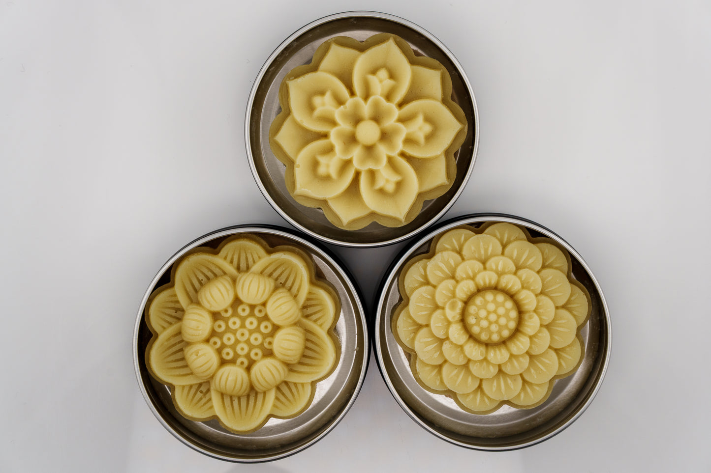 Three Island Natural Skincare lotion bars with floral designs on a white background